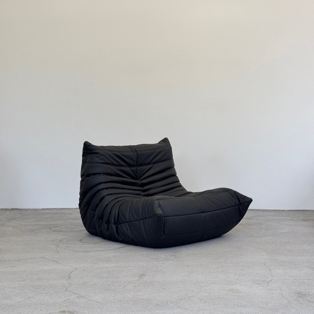 Black togo chair on a gray floor with a white wall background