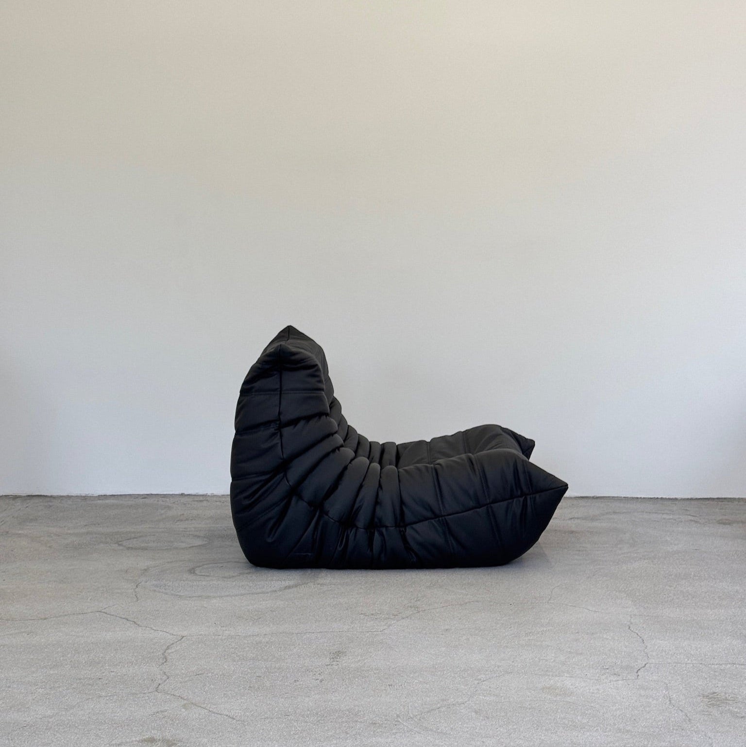 Black togo chair on a gray floor with a white wall background