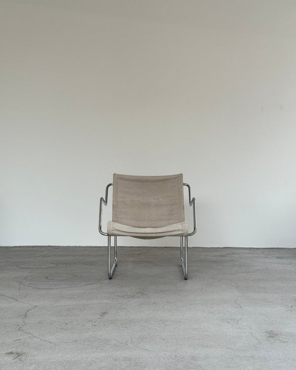 Beige chair with metal frame on a gray floor and white wall