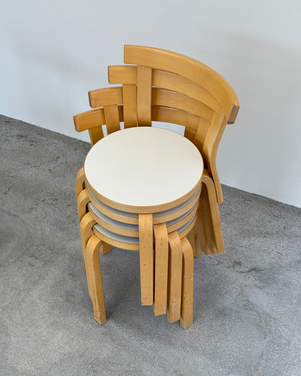 Wooden artek chairs stacked on a gray surface