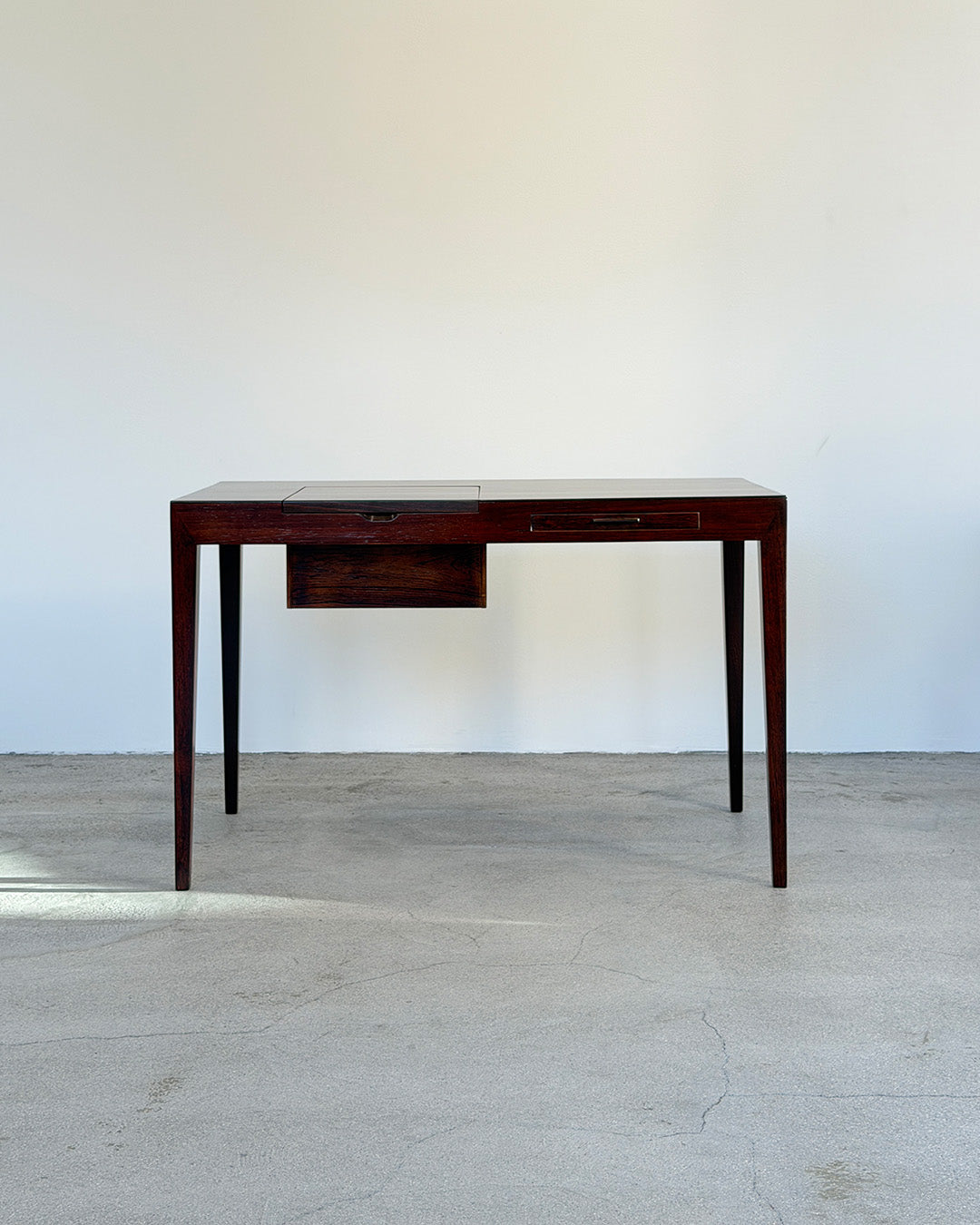 Wooden desk against a white wall on a light-colored floor