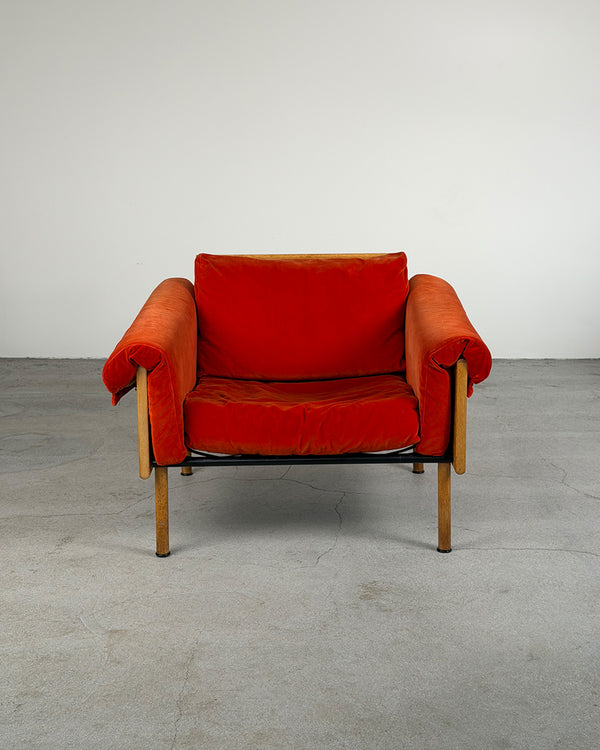 Red armchair with wooden frame on a gray floor and white wall background