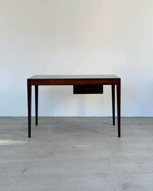 Wooden desk against a plain white wall on a concrete floor