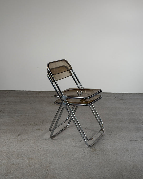 Foldable chair with brown seat and backrest on a gray floor and white wall background