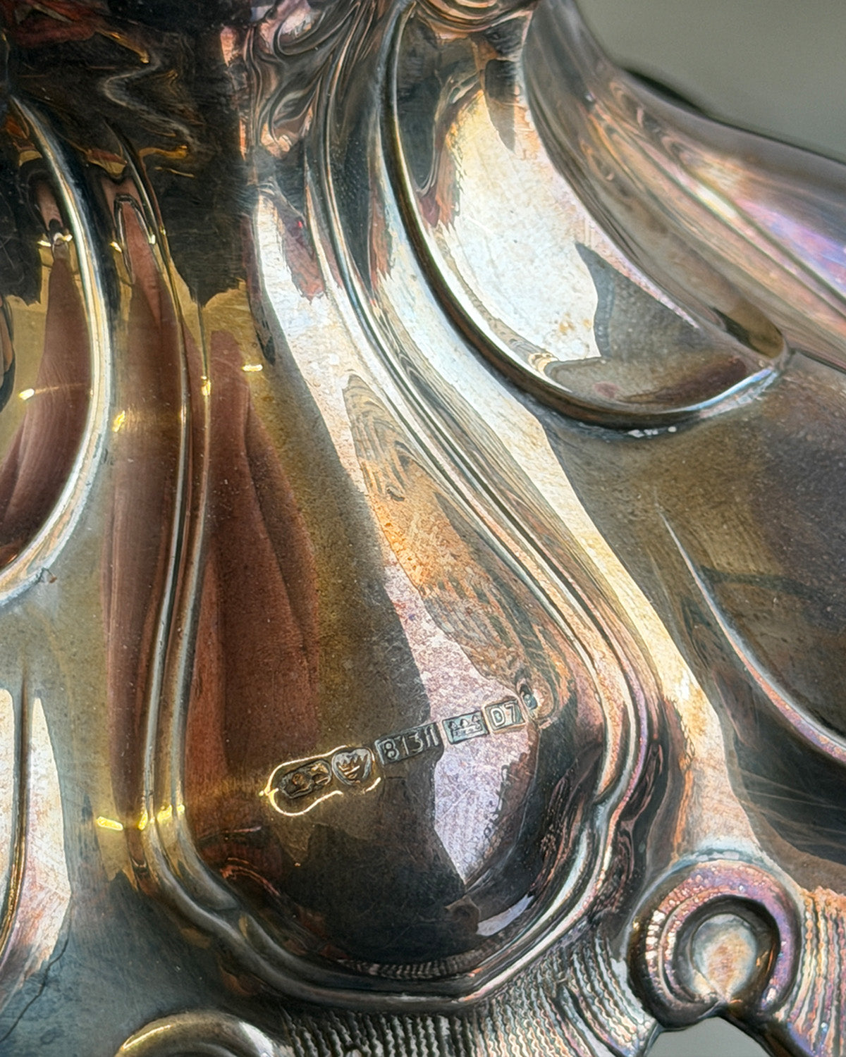Close-up of a silver candle holder with visible hallmarking on a reflective surface.