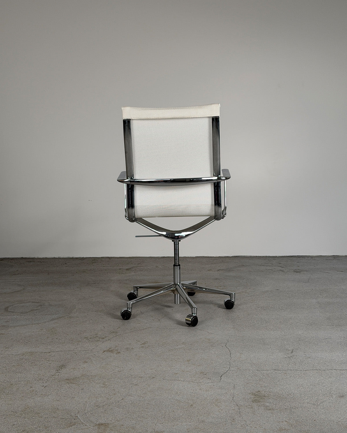 Modern office chair with white seat and backrest on a gray floor and background