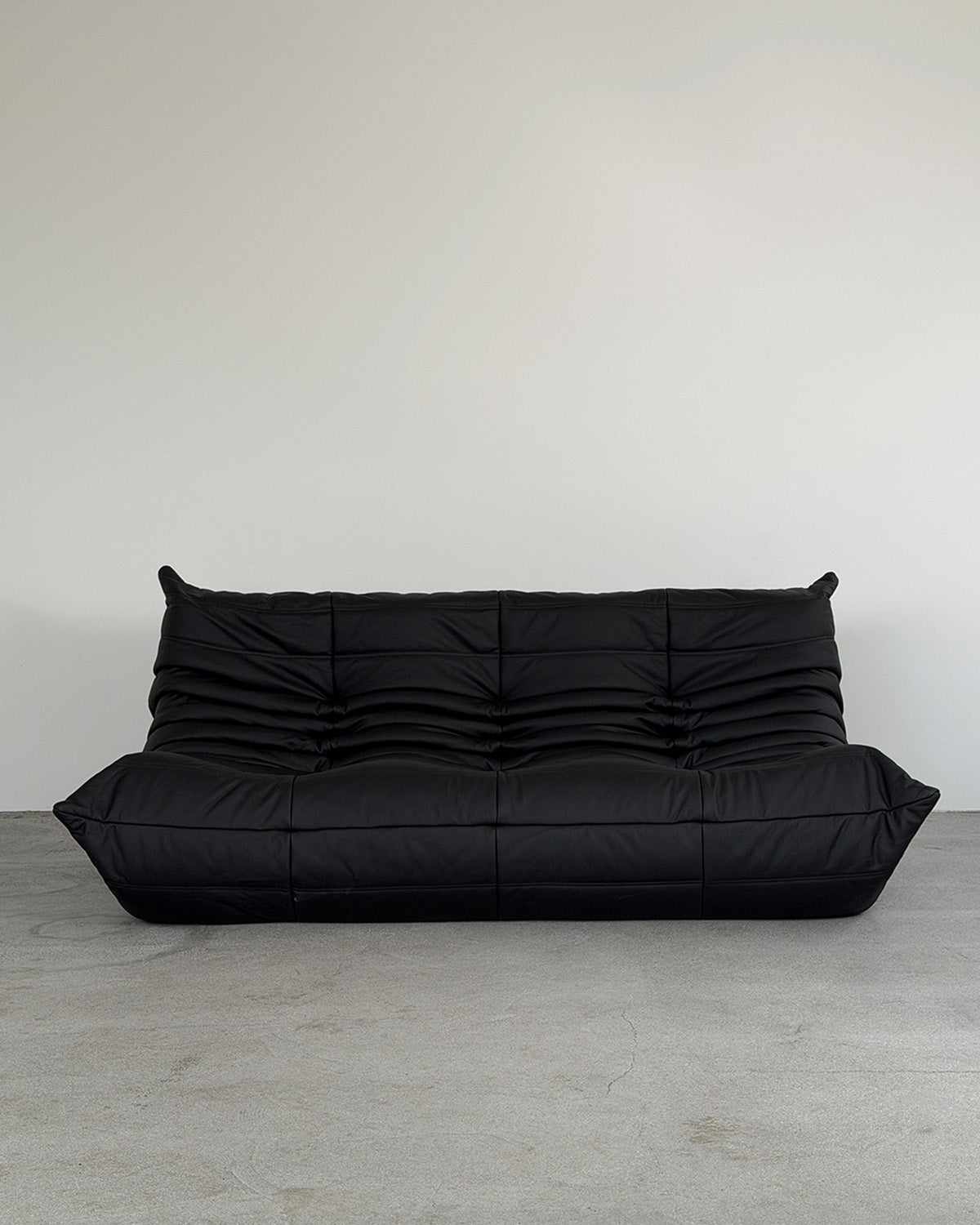 Black leather three-seater Togo sofa by Michel Ducaroy for Ligne Roset, shown on a plain background.