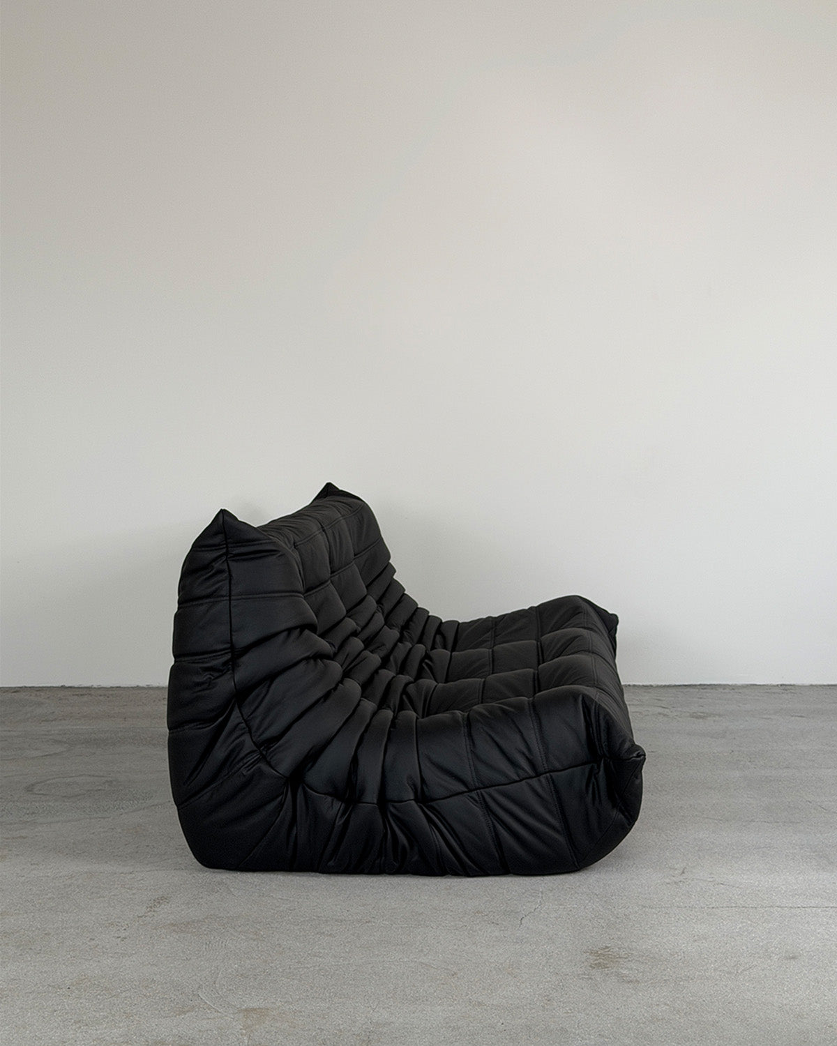 Black leather three-seater Togo sofa by Michel Ducaroy for Ligne Roset, shown on a plain background.