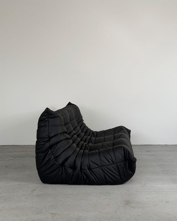 Black leather three-seater Togo sofa by Michel Ducaroy for Ligne Roset, shown on a plain background.