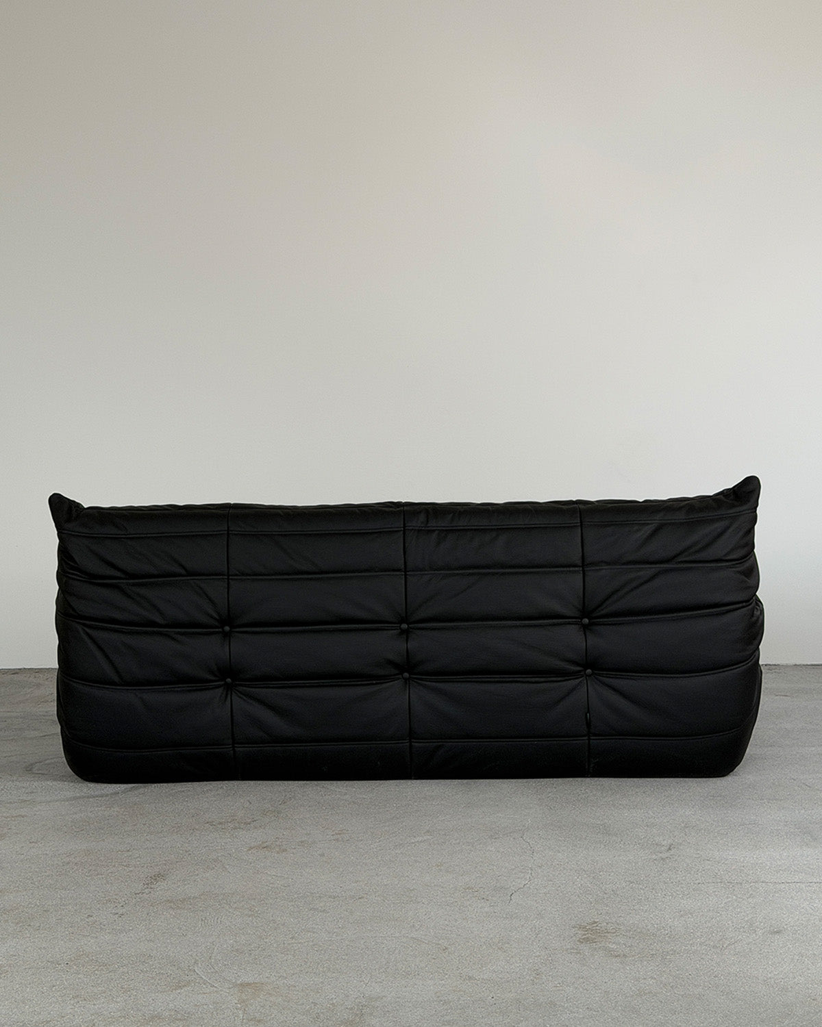 Black leather three-seater Togo sofa by Michel Ducaroy for Ligne Roset, shown on a plain background.