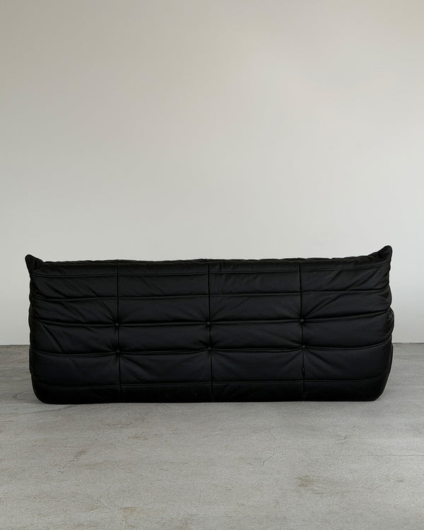 Black leather three-seater Togo sofa by Michel Ducaroy for Ligne Roset, shown on a plain background.