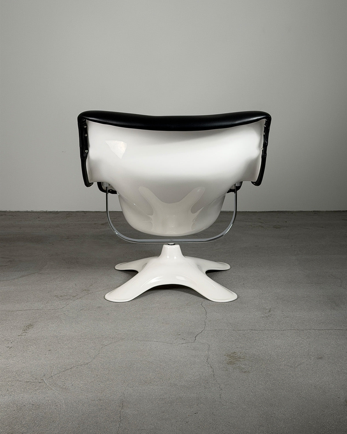 Modern Karuselli chair with black backrest and white seat on a gray floor and background